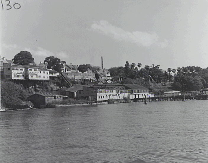 Black and white image from the water showing the box factory buildings on the cliff