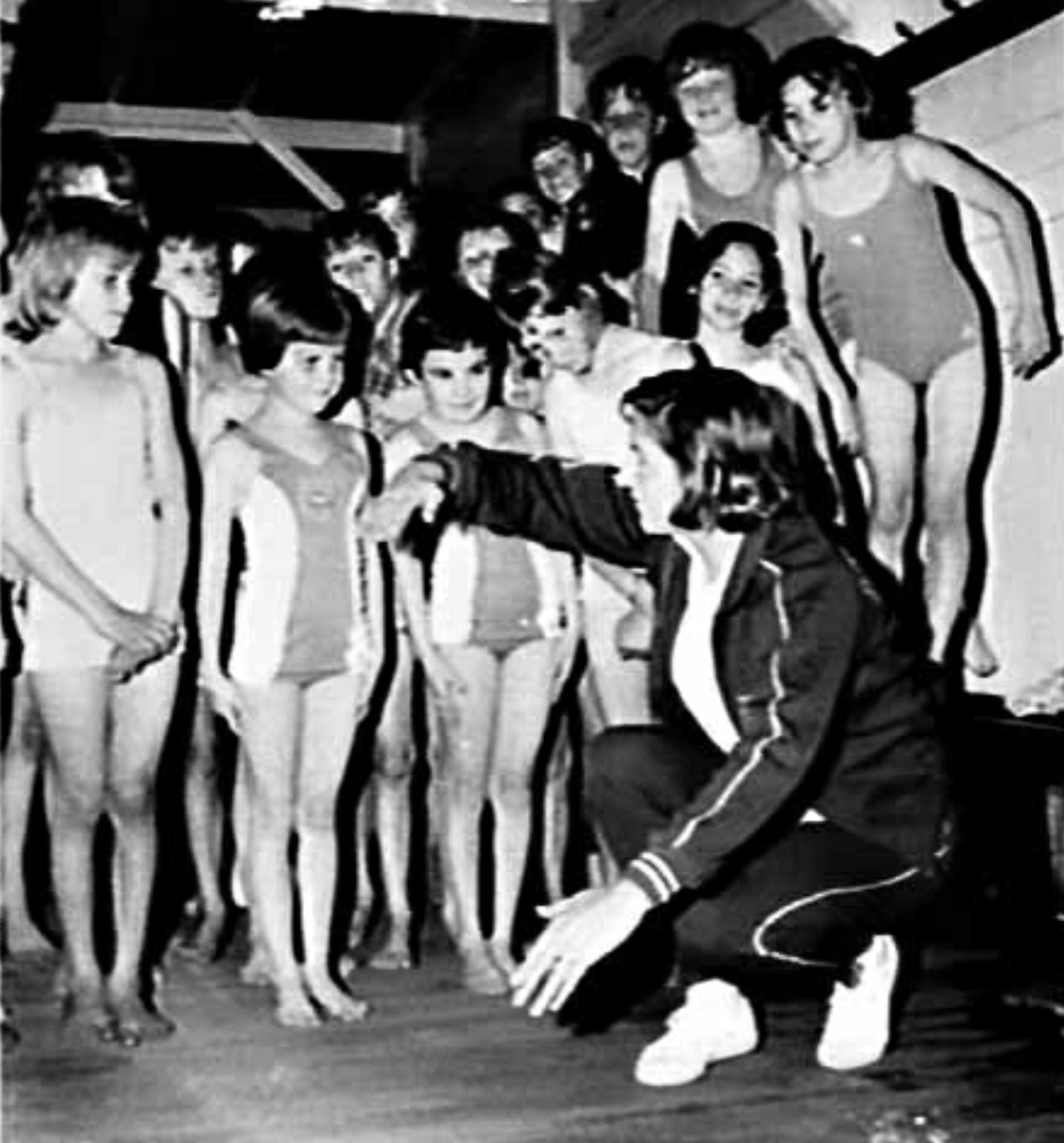 Black and White photo with Dawn Fraser demonstrating, to a group of young children how the swim in the Balmain pool